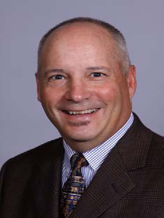 David Hall wearing black suit with brown and black tie.